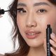 A woman is applying mascara to her eyes