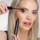 A woman carefully applies mascara to her eyelashes