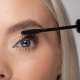 A woman uses a mascara brush to apply mascara