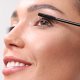 A woman is applying mascara with a brush