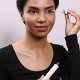 A woman applies mascara with a brush