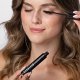 A woman carefully applies mascara to enhance her eyelashes