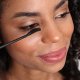 A woman applies mascara to her eye