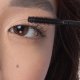 A woman is applying mascara with a brush