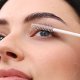 A woman uses a brush to apply mascara