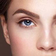 Model with deep blue eyes and thick brows looking at the camera